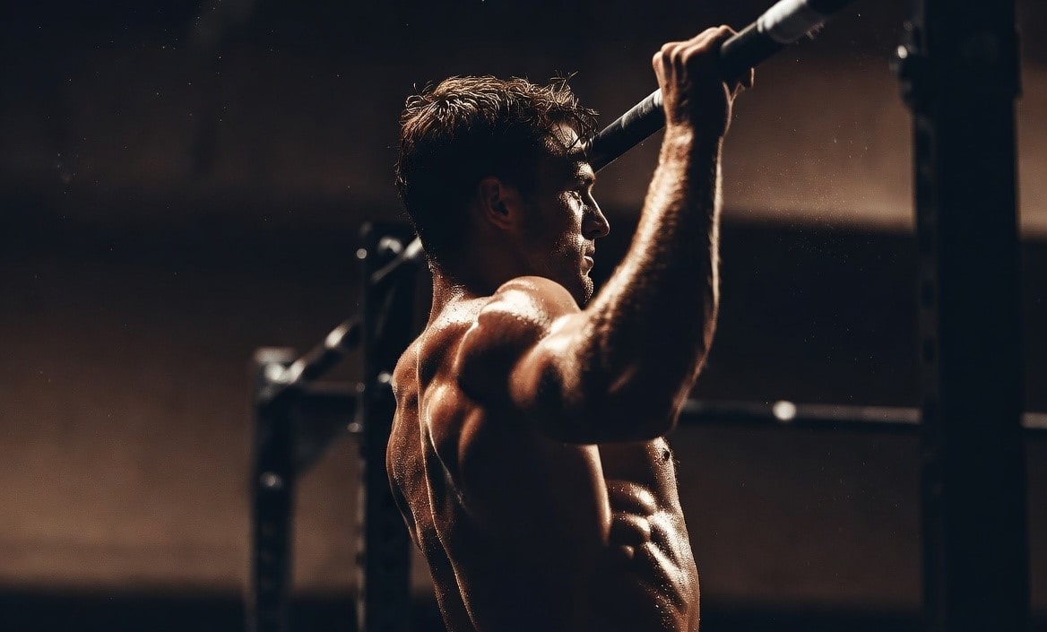 Athlete performing barbell back squat in a dark gym